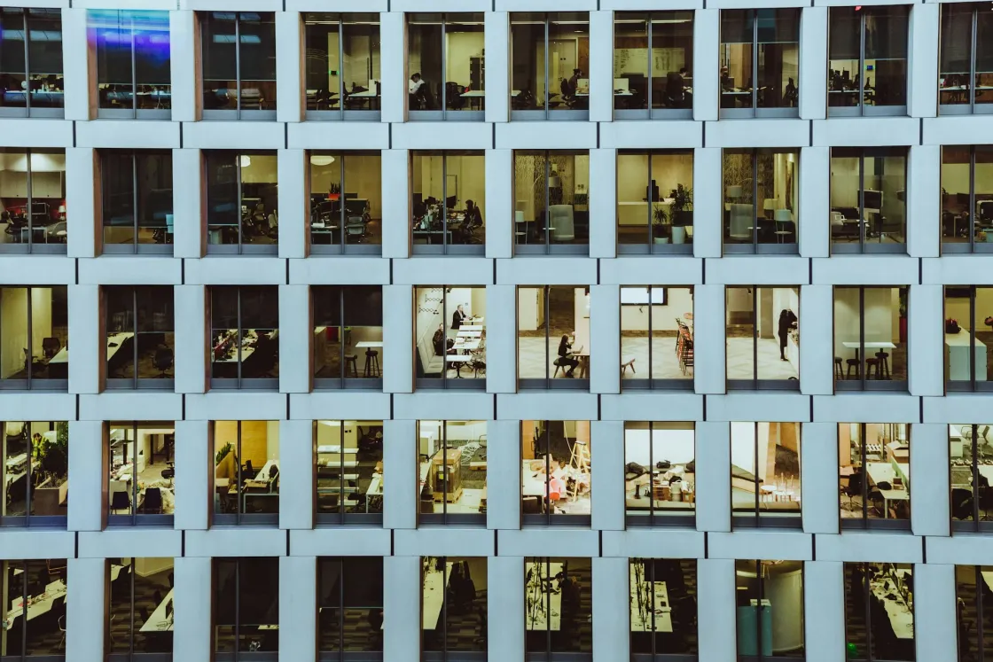 A grid of office windows showing different teams and workspaces, highlighting transparency in modern workplace culture.